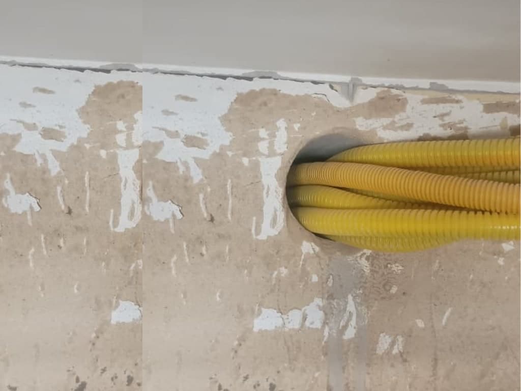 Furo em parede de concreto com quatro eletrodutos corrugados amarelos passando