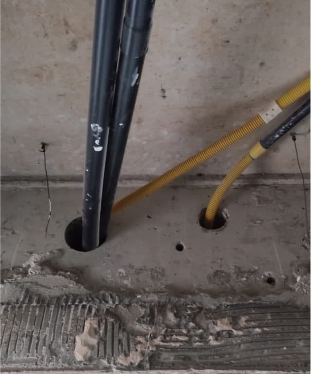 Furos em parede de concreto com tubulações e eletroduto passando