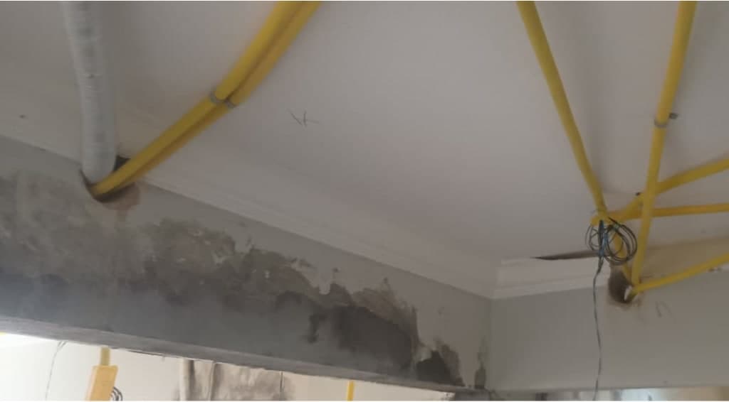 Eletrodutos amarelos passando por furos em viga de concreto, junto à laje